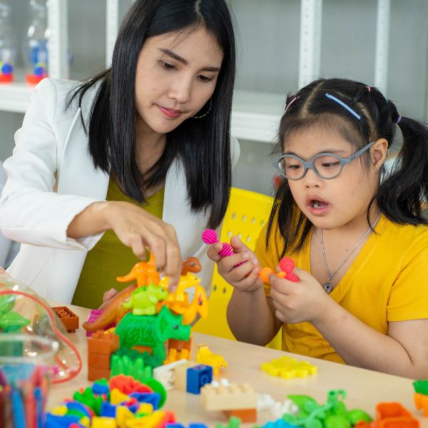 child playing with toys while therapist watches